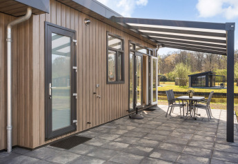 Modern Zandduin Deluxe lodge at De Tien Heugten in the Netherlands, shown with covered patio and chairs.