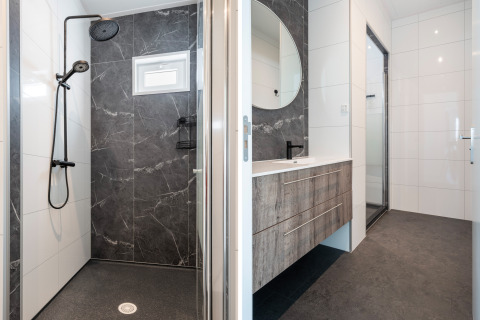 Moderne badkamer in Zandduin Deluxe-lodge bij De Tien Heugten met douche, wastafel en spiegel.