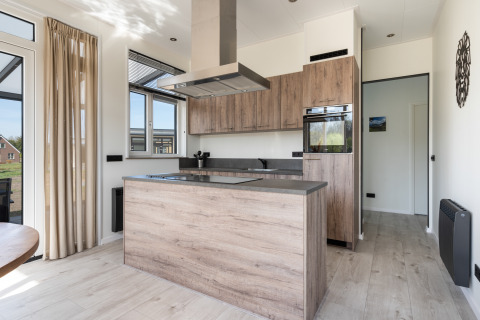 Cucina moderna nella Zandduin Deluxe Lodge a De Tien Heugten, Paesi Bassi, con accenti in legno chiaro.