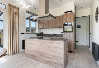 Cucina moderna nella Zandduin Deluxe Lodge a De Tien Heugten, Paesi Bassi, con accenti in legno chiaro.