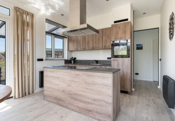 Modern kitchen in the Zandduin Deluxe lodge at De Tien Heugten, Netherlands, featuring light wood accents.