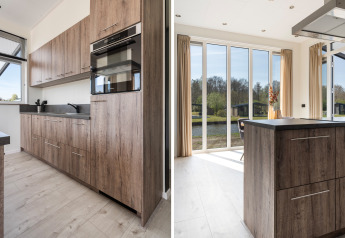 Moderne keuken met houten kasten en grote ramen in Zandduin Deluxe lodge bij De Tien Heugten, Nederland.