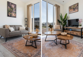 Salon du lodge Zandduin Deluxe à De Tien Heugten, Pays-Bas, avec déco moderne, canapé et grandes fenêtres.