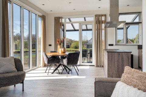 Lichte, moderne woon- en eetkamer in Zandduin Deluxe-lodge bij De Tien Heugten, Nederland, met grote ramen.
