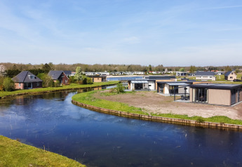 Modern holiday lodges by a winding pond at De Tien Heugten, Zandduin Deluxe, surrounded by Dutch nature.