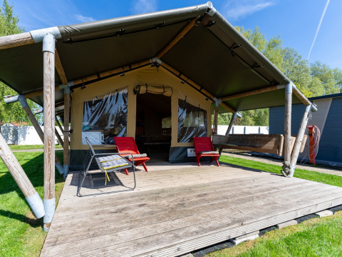Safaritent bij Marina Heeg in Nederland met houten veranda, rode stoelen en een ontspannen buitengevoel.