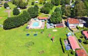 Vista aerea di Camping La Colline in Belgio con piscina, area giochi, prati verdi e bungalow vacanza.