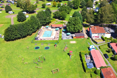 Vista aerea di Camping La Colline in Belgio con piscina, area giochi, prati verdi e bungalow vacanza.