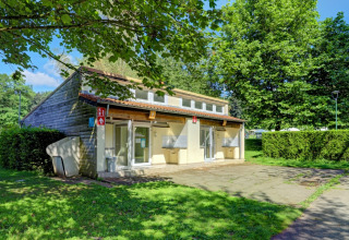 Communal building at Camping La Colline holiday park, surrounded by greenery and trees in Belgium Luxembourg.