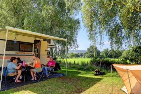 Family camping at Camping La Colline in Belgium Luxembourg, relaxing by RV with green fields and sunshine.