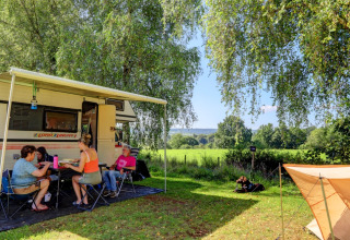 Famiglia in campeggio a Camping La Colline in Belgio Lussemburgo, relax vicino al camper e aree verdi.