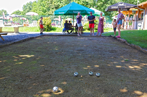 Menschen spielen Boule unter grünen Sonnenschirmen im Ferienpark Camping La Colline in Belgien Luxemburg.