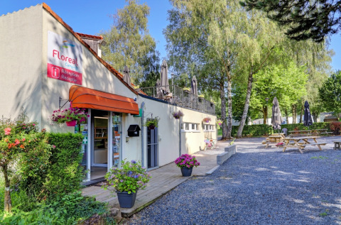 Rezeption vom Camping La Colline im Ferienpark Belgien Luxemburg, mit Blumen und Picknicktischen im Freien.