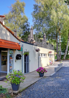 Recepción de Camping La Colline en el parque vacacional de Bélgica Luxemburgo, con flores y mesas exteriores.