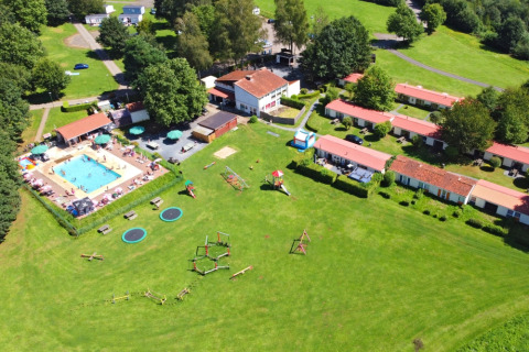 Aerial view of Camping La Colline holiday park in Belgium with swimming pool, playground and lodges.