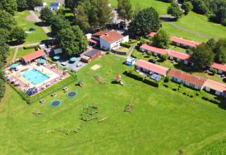 Vista aerea del villaggio vacanze Camping La Colline in Belgio con piscina, parco giochi e alloggi.