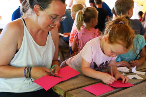 An adult and a child do crafts together at a table at Camping La Colline, Belgium Luxembourg.