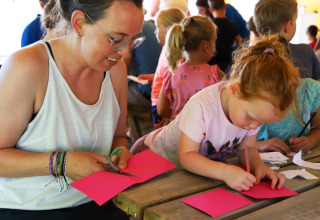 Un adulte et un enfant font des travaux manuels à une table au Camping La Colline, Belgique Luxembourg.
