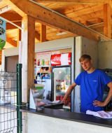 Joven en puesto de helados al aire libre en Camping La Colline, Bélgica, con cartel de Ben & Jerry's.