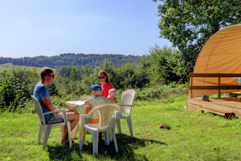 Familie genießt Mahlzeit im Freien bei Camping La Colline, Belgisch Luxemburg, Belgien, an einem sonnigen Tag.