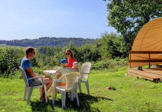 Family enjoying meal outdoors at Camping La Colline holiday park in Belgian Luxembourg, Belgium in summer.