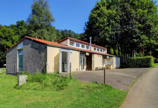 Photo of a communal building at Camping La Colline, Belgium Luxembourg, surrounded by greenery and trees.