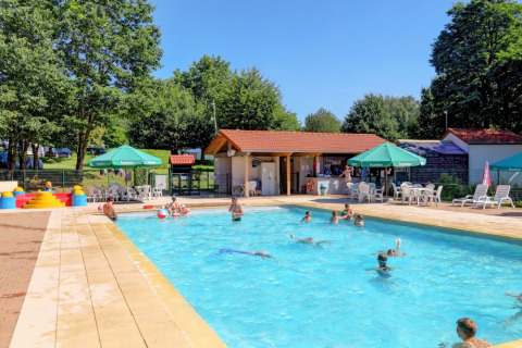 Schwimmbadbereich mit spielenden Gästen, Liegestühlen und Sonnenschirmen im Camping La Colline, Belgien.