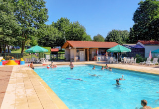 Area piscina con ospiti che nuotano e si rilassano, sedie a sdraio e ombrelloni a Camping La Colline.