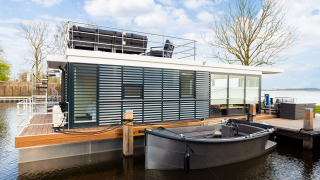 Houseboat moderno 'de Valreep' a Welcome In - Friesland, Paesi Bassi, con terrazza e piccola barca.