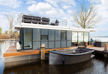 Houseboat moderno 'de Valreep' a Welcome In - Friesland, Paesi Bassi, con terrazza e piccola barca.
