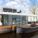 Moderne husbåd 'de Valreep' ved Welcome In - Friesland, Nederlandene, med tagterrasse og lille båd.