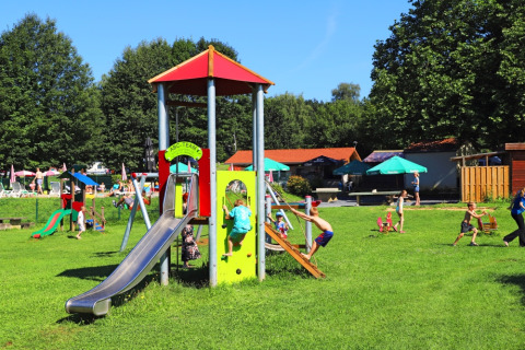 Bambini si divertono giocando nell’area giochi di Camping La Colline, parco vacanze in Belgio Lussemburgo.