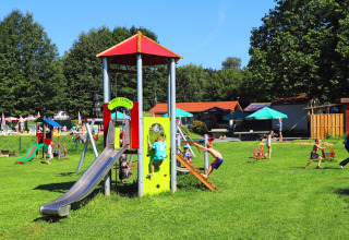 Bambini si divertono giocando nell’area giochi di Camping La Colline, parco vacanze in Belgio Lussemburgo.