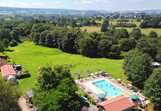 Aerial view of Camping La Colline holiday park in Belgian Luxembourg, Belgium, showing pool and greenery.