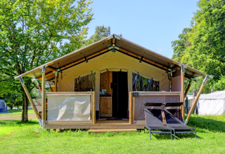 Tenda glamping al Camping La Colline, Belgio Lussemburgo, con sdraio e ambientazione verde lussureggiante.