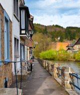 Joli chemin en bord de rivière bordé de maisons en pierre, cadre idéal dans un parc de glamping verdoyant.