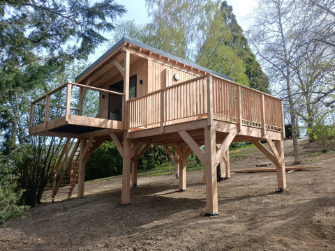 Cabaña de madera elevada con amplia terraza en Hameau de l'Ourthe, parque vacacional en Luxemburgo, Bélgica.