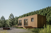 Moderne træhytte ved Hameau de l'Ourthe feriepark, omgivet af skov og grønne bakker i Belgien.