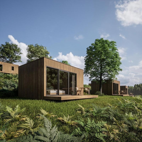 Modern wooden cabins with large windows in a lush, green setting at Hameau de l'Ourthe, Belgium.
