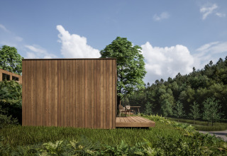 Wooden cabin at Hameau de l'Ourthe holiday park, Belgium Luxembourg, surrounded by lush green trees.