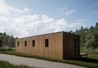 Modern wooden cabin at Hameau de l'Ourthe holiday park, Belgium, surrounded by greenery and blue sky.