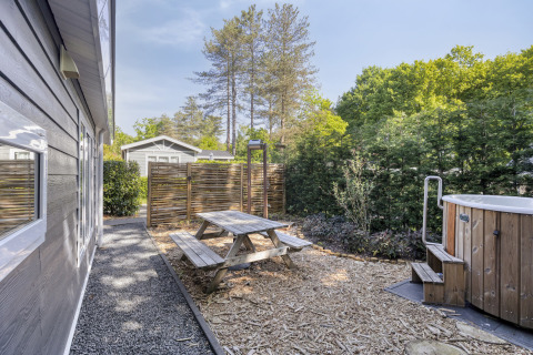 Zona exterior en Wellness Lodge con mesa de picnic, jacuzzi y valla de privacidad en De Thijmse Berg, Países Bajos.