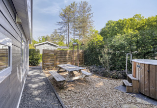 Outdoor area at Wellness Lodge featuring a picnic table, hot tub, and privacy fence at De Thijmse Berg, Netherlands.