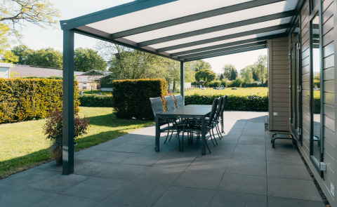 Overdekt terras bij Veluwe Villa in vakantiepark De Boshoek in Nederland met tuin en eettafel.