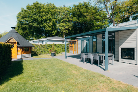 Buitenruimte bij Veluwe Villa op Vakantiepark De Boshoek, Nederland, met terras, zitje en houten hut.