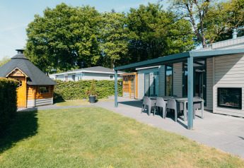 Area esterna di Veluwe Villa, De Boshoek, Paesi Bassi, con patio, tavolo, sedie e casetta di legno.