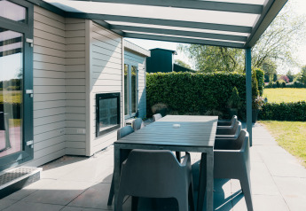 Patio coperto moderno con tavolo da pranzo e sedie a Veluwe Villa, Holiday park De Boshoek, Paesi Bassi.