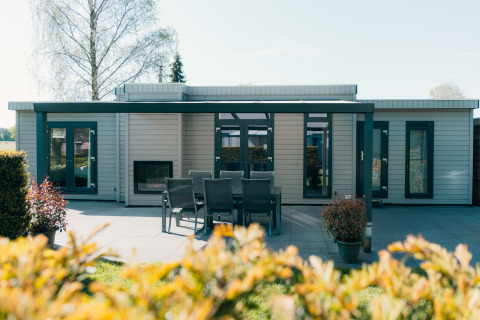 Modern Veluwe Villa lodge with outdoor dining area and patio at Holiday park De Boshoek, Netherlands.