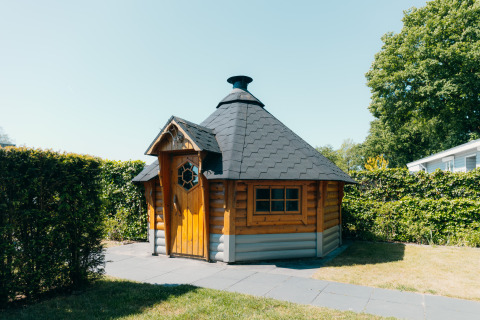 Udendørsbillede af en træhytte på Veluwe Villa ved ferieparken De Boshoek i Holland på en solskinsdag.
