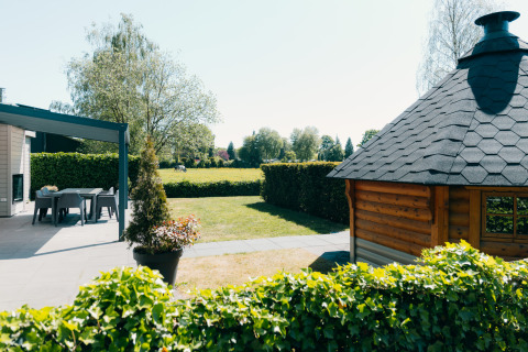Buitenzicht bij Veluwe Villa op vakantiepark De Boshoek in Nederland, met terras en houten chalet.